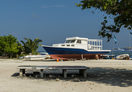 Colorful boat lying on the beach of the tropical island, against a bright blue sky and turquoise water, Maldives, Indian Oceanの写真素材