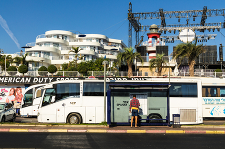 EILAT, ISRAEL - November 7, 2017: In the foreground - tourist study the bus schedule, in the background - "Club hotel" and mini solar power station, Eilat, Israel. Travel and tourism conceptのeditorial素材