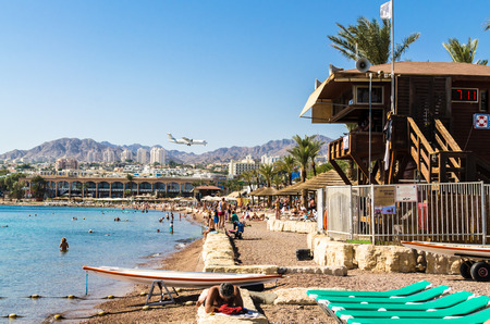 EILAT, ISRAEL - November 7, 2017: city of Eilat with tourists and twin-engine turboprop aircraft landing on the background of urban white buildings and mountain peaks, Eilat, Israel. Travel and tourism conceptのeditorial素材