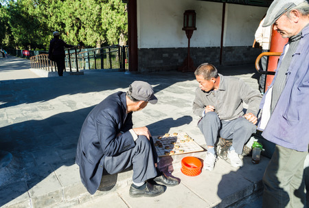 BEIJING, CHINA - October 15, 2013: Elderly men playing Chinese chess, called Xiangqi in central park near Temple of Heaven, Beijing, China. Chess is one of the most popular strategy game in Chinaのeditorial素材