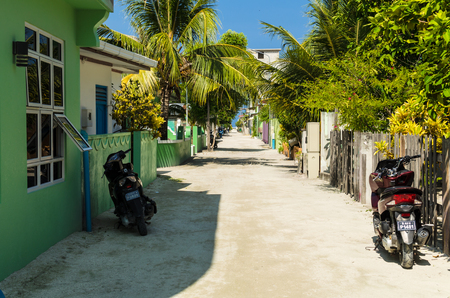Maldives - November 20, 2017: The central street of the Huraa island with one-story houses and tall palm trees overlooking the Indian Ocean, Kaafu Atoll, Kuda Huraa Island, Maldivesのeditorial素材