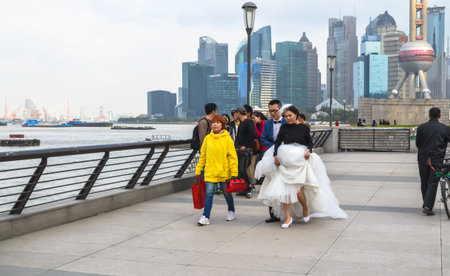 SHANGHAI, CHINA - October 26, 2013: Young couple in wedding dress walking along the promenade at the...
