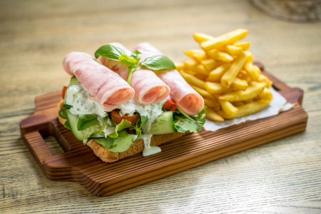 Rolled ham sandwich with fresh dill sauce, cucumbers, cherry tomatoes, lettuce and french fries