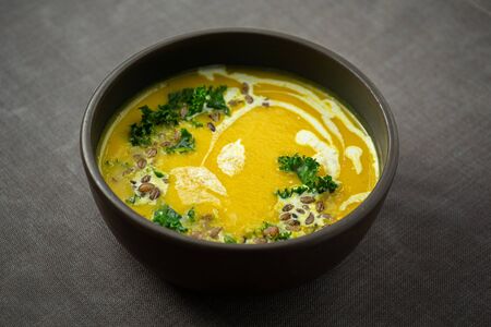 Pumpkin and kale cream soup with sweet cream, hulled barley and herbsの写真素材