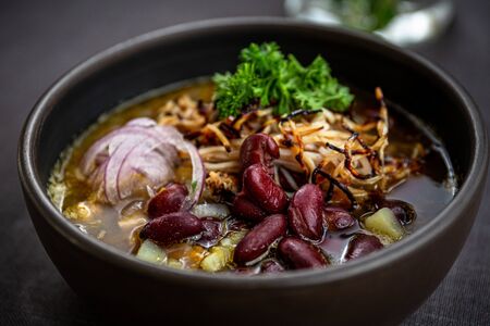Bean soup with smoked pork, potatoes, herbs, onions, carrots and sour creamの写真素材