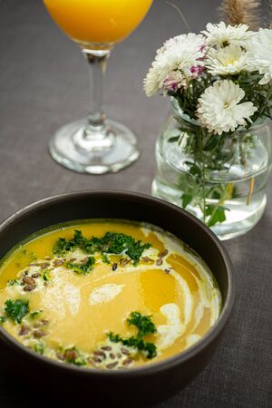 Pumpkin and kale cream soup with sweet cream, hulled barley and herbsの写真素材