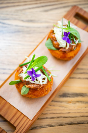 Breaded and deep fried meatball with sauce on top on a wooden plate