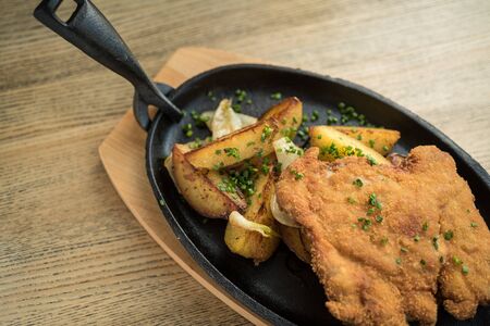 Breaded pork meat with fried potatoes and green seasoningの写真素材