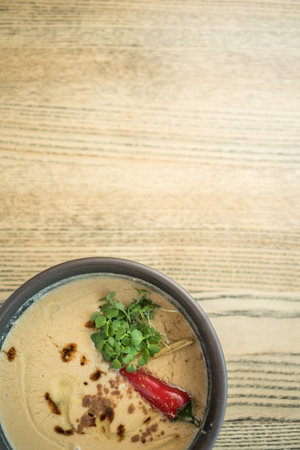 Vegetable cream soup with a whole red chili pepper in a stone bowl