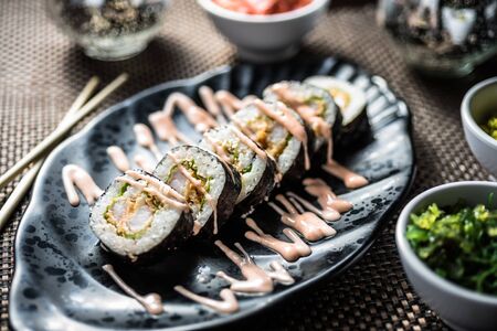 Sushi maki with tempura prawns, green salad and cream cheese with chili sauce over themの写真素材
