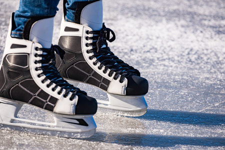 Detail of the black and white mens ice skates in action on ice