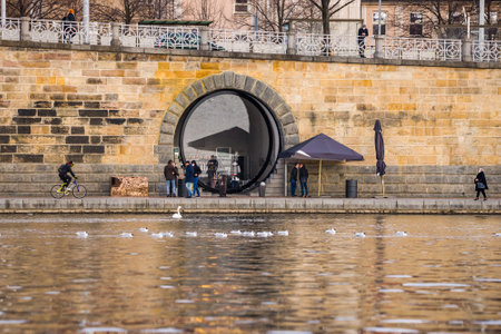 Prague, Czech republic - March 12. People wearing face mask protection on public places on empty Rasinovo embankment by Moldau by giant glass lens windowsのeditorial素材