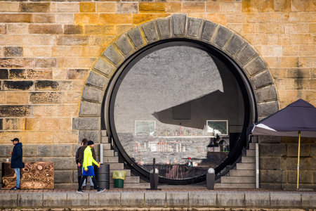 Prague, Czech republic - March 12. People wearing face mask protection on public places on empty Rasinovo embankment by Moldau by giant glass lens windowsのeditorial素材