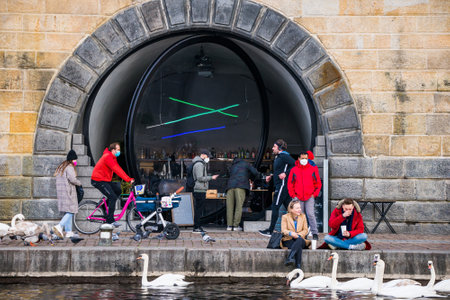 Prague, Czech republic - March 12. People wearing face mask protection on public places on empty Rasinovo embankment by Moldau by giant glass lens windowsのeditorial素材