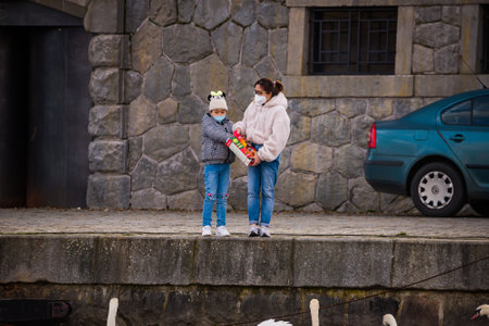 Prague, Czech republic - March 12. Children with parents playing with face mask protection on public places in riverbank by Moldau and feeding birds while playgrounds are closedのeditorial素材