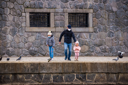 Prague, Czech republic - March 12. Children with parents playing with face mask protection on public places in riverbank by Moldau and feeding birds while playgrounds are closedのeditorial素材