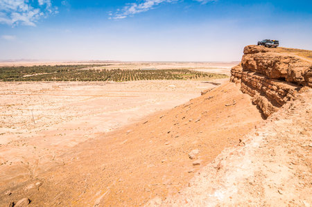 Erfoud, Morocco - April 15, 2015. Two vintage off road cars parked on the rock cliff above desert landscapeのeditorial素材