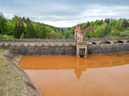 Czech republic, Talsperre Les Kralovstvi (Forest Kingdom) - May 15, 2021. Aerial view of historic hydraulic water dam with orange water in river Elbeのeditorial素材