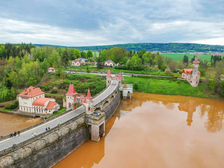 Czech republic, Talsperre Les Kralovstvi (Forest Kingdom) - May 15, 2021. Aerial view of historic hydraulic water dam with orange water in river Elbeのeditorial素材