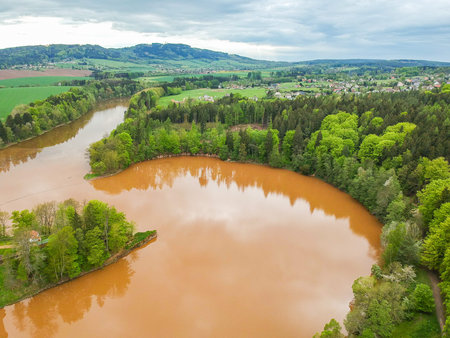 Czech republic, Talsperre Les Kralovstvi (Forest Kingdom) - May 15, 2021. Aerial view of historic hydraulic water dam with orange water in river Elbeのeditorial素材
