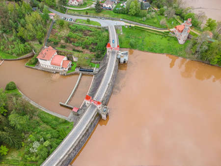 Czech republic, Talsperre Les Kralovstvi (Forest Kingdom) - May 15, 2021. Aerial view of historic hydraulic water dam with orange water in river Elbeのeditorial素材