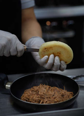 chef preparing Venezuelan arepa stuffed with shredded meat typical foodの写真素材
