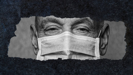 An elderly man in a medical mask looks through a window of torn paper. Risk group. Concept of...