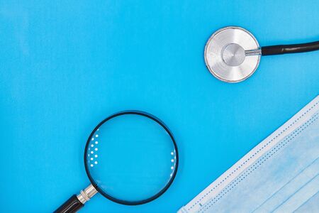 Stethoscope or phonendoscope, magnifying glass and medical mask on the blue background with copy space. Concept of protection from Coronavirus. Closeupの写真素材
