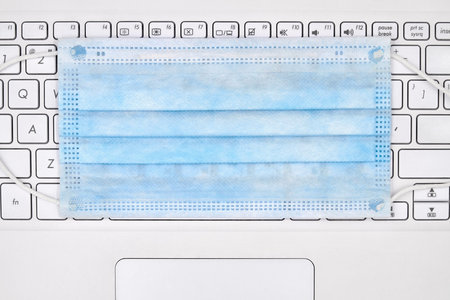 Concept work from home. Protective madical face mask lies on a notebook keyboard. Quarantine during...