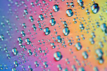 Water drops with reflection of the rainbow. Colorful abstract background. Blue, green, red and yellow abstract rainbow background. Closeup, selective focusの写真素材
