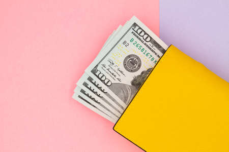 Close-up of yellow wallet with 100 dollar banknotes on a colored backgroundの写真素材
