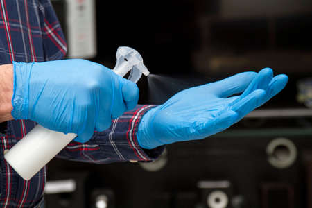 Man in blue protective gloves disinfects his hands in an audio and video equipment store. Protection from bacteria and viruses.の写真素材
