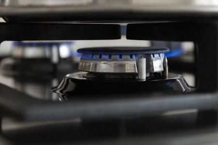 Gas burning from a kitchen gas stove. Blue gas flame on hob. Closeup, selective focus