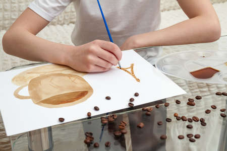 Coffee drawings. Girl draws a coffee cup using coffee instead of paintsの写真素材