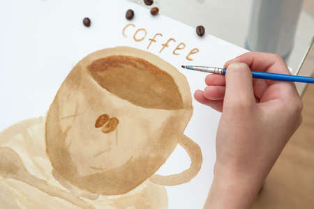 Coffee drawings. Girl draws a coffee cup using coffee instead of paintsの写真素材