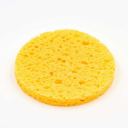 A round yellow cosmetic sponge pad for face make-up cleaning on white backgroundの写真素材