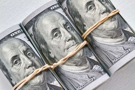 American one hundred banknotes rolled up as a tubule. Light background, closeup, selective focusの写真素材
