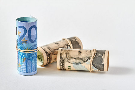 Twenty Euro bill rolled up as a tubule stands on the background of twenty dollar bills. Concept of...