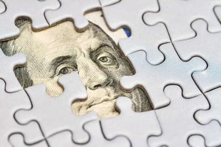 Dollar puzzle, business concept of solution. Dollar bill and puzzle pieces. Portrait of american president Franklin. Closeup, selective focusの写真素材