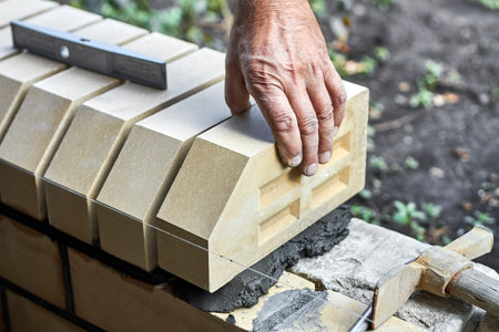 Bricklayer installing bricks on the new fence from facing bricks.