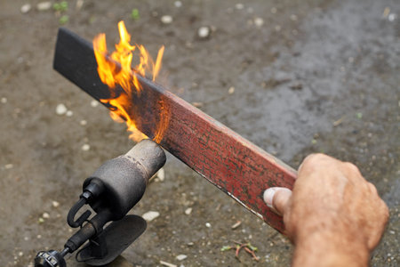 A man is burning the board using the old rusty blowtorch. Handmaking manufacturing process of burnt...