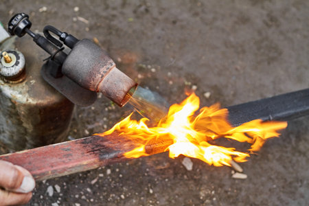 A man is burning the board using the old rusty blowtorch. Handmaking manufacturing process of burnt...