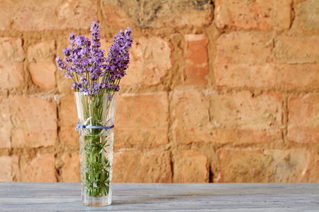 Bouquet of fresh purple lavender in a glass vase on the brick wall background