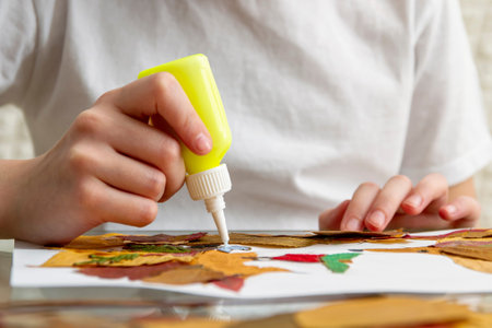 Girl makes an application from dry leaves. Children applique on the autumn theme. Hedgehogs and...