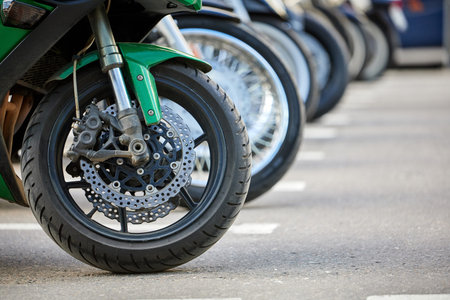 Row of motorcycle wheels in a parking lot. Close-up, selective focus