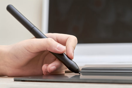 Girl draws on a graphics tablet with pen. Close-up, selective focus