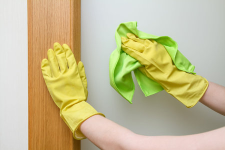 Hands with a duster cleaning the door. Closeup