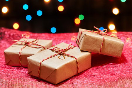 Christmas or New Year gift boxes on red cloth against a background of colorful lights