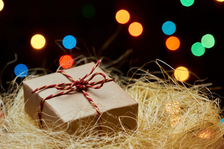 Christmas or New Year gift box in the hay against a background of colorful lights. Close-up,...