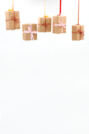 Christmas or New Year gift boxes with colorful ribbons hang on white background with copy space